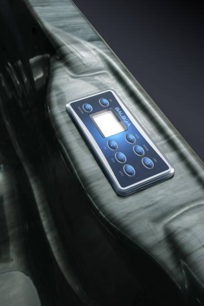 Panneau de contrôle BALBOA bleu rétroéclairé sur une surface de spa moderne, affichant des boutons et un écran lumineux.