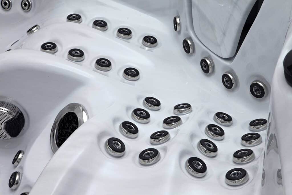 Intérieur moderne d'un bain à remous blanc avec de nombreux hydrojets circulaires et grilles de haut-parleurs en métal.