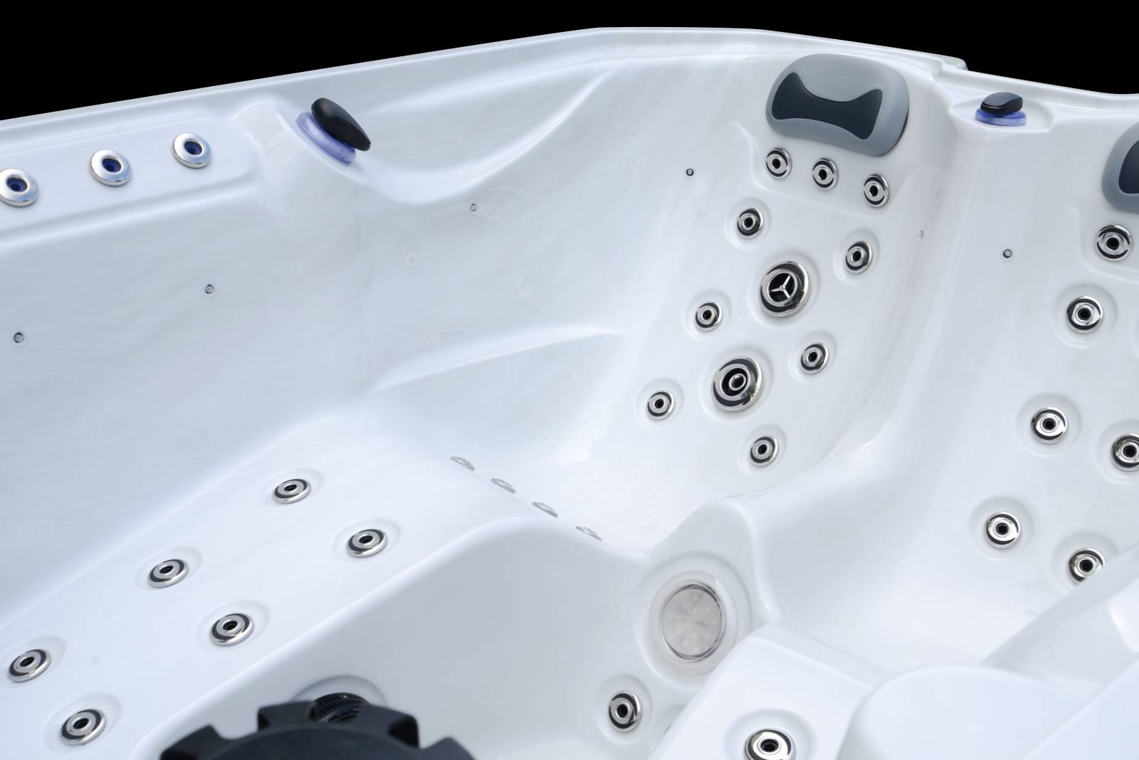Intérieur blanc brillant d'un spa ou jacuzzi avec de nombreux jets d'hydrothérapie chromés, des appuie-têtes gris confortables et des boutons de contrôle noirs.
