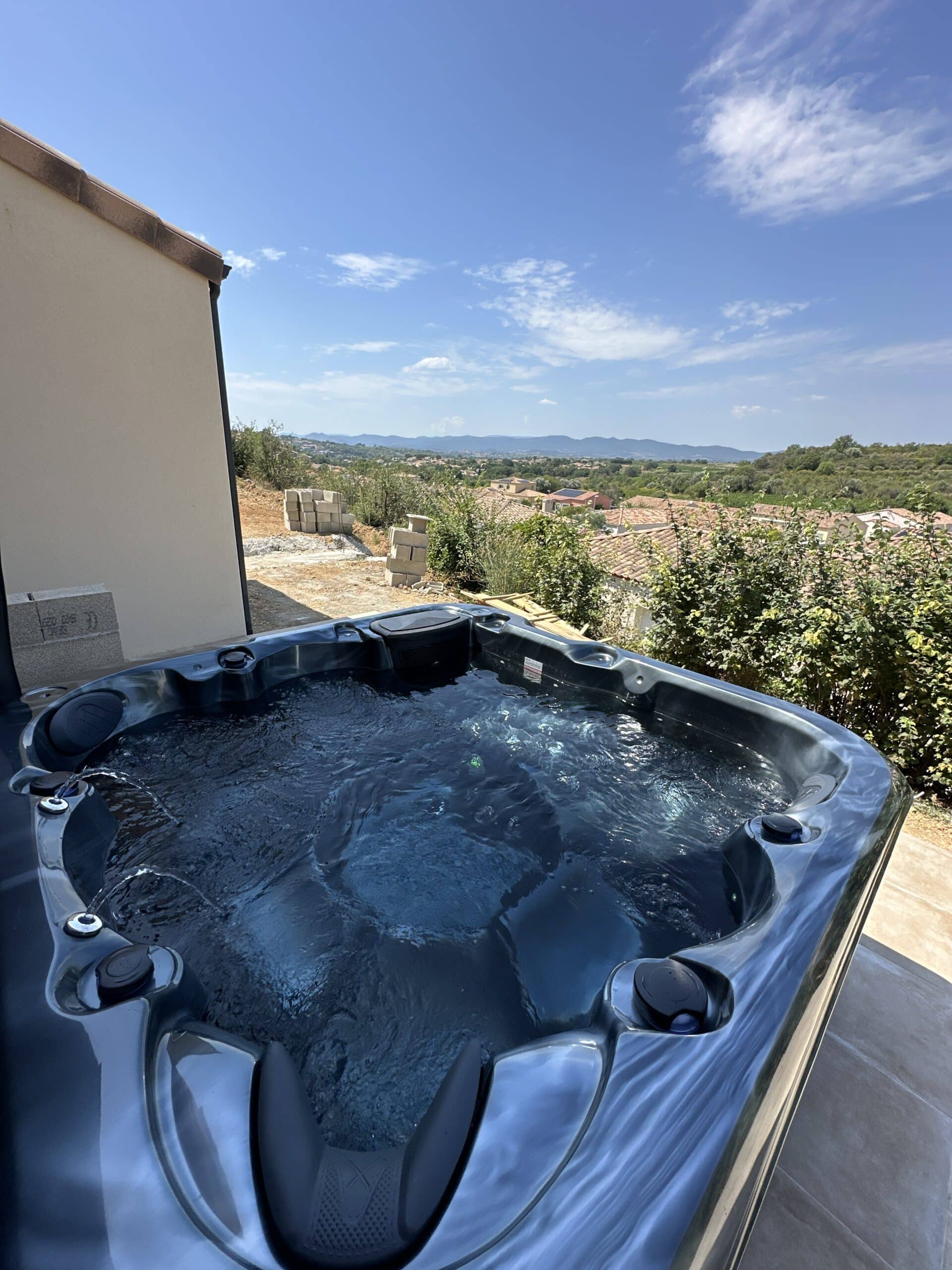 Jacuzzi moderne sur une terrasse ensoleillée offrant une vue panoramique imprenable sur les toits provençaux et les collines.