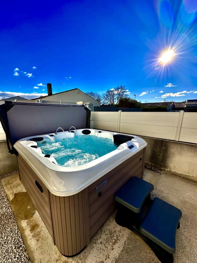 Spa Vendôm extérieur bouillonnant sous un ciel bleu éclatant. Spa Vendôm extérieur moderne et bouillonnant sur une terrasse ensoleillée. Ciel bleu intense et lumineux. Marches d'accès grises.